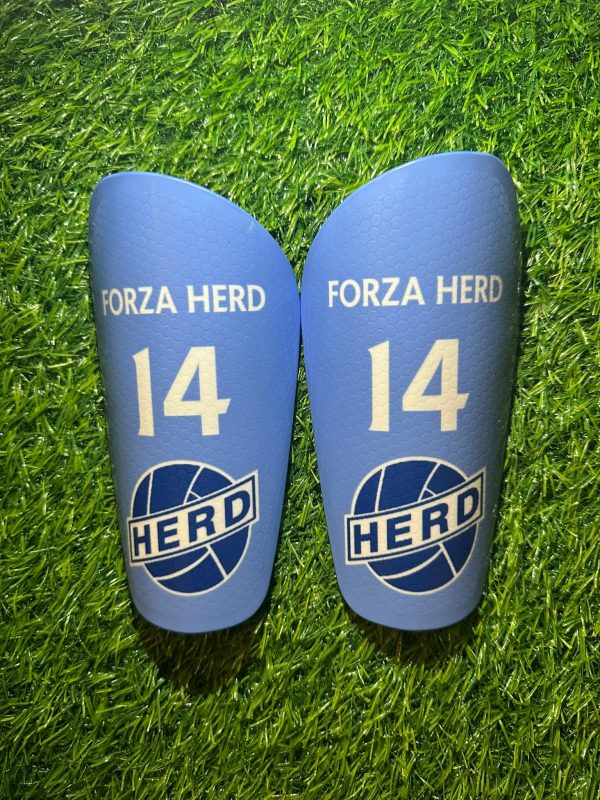 Standard personalised shin pads with blue backdrop and white text with grassroots logo.