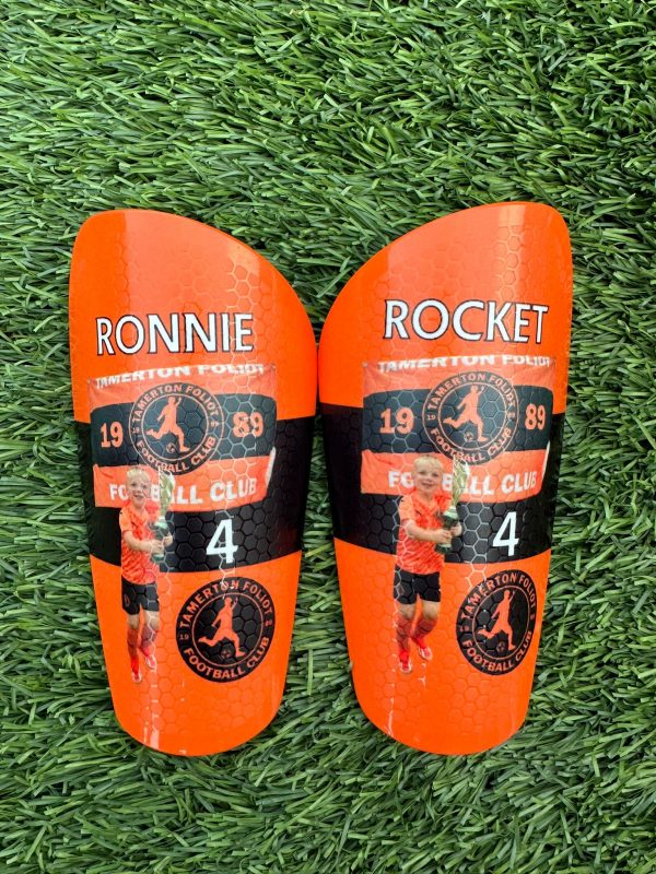 Pro personalised shin pads orange backdrop.