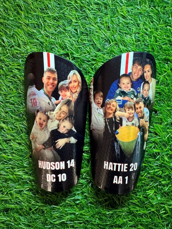 Elite personalised shin pads with black, white and red backdrop and family together.