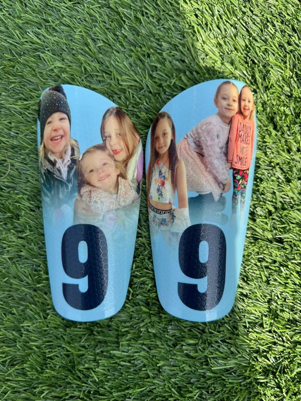 Elite personalised shin pads. Light blue backdrop with black text and family image.