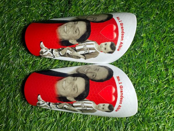 Elite personalised shin pads with white and red backdrop and family photos.