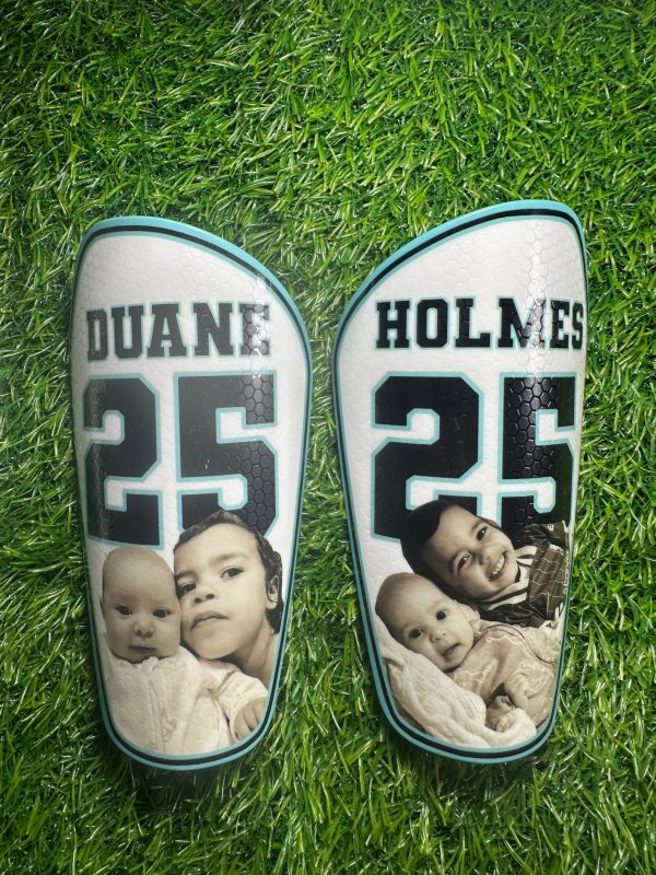 Elite personalised shin pads with white backdrop and black text and black and white family photos.
