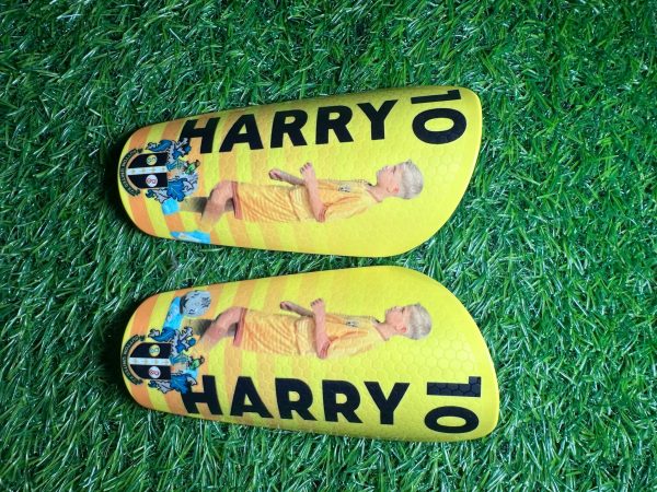 Elite personalised shin pads with yellow background and black text.